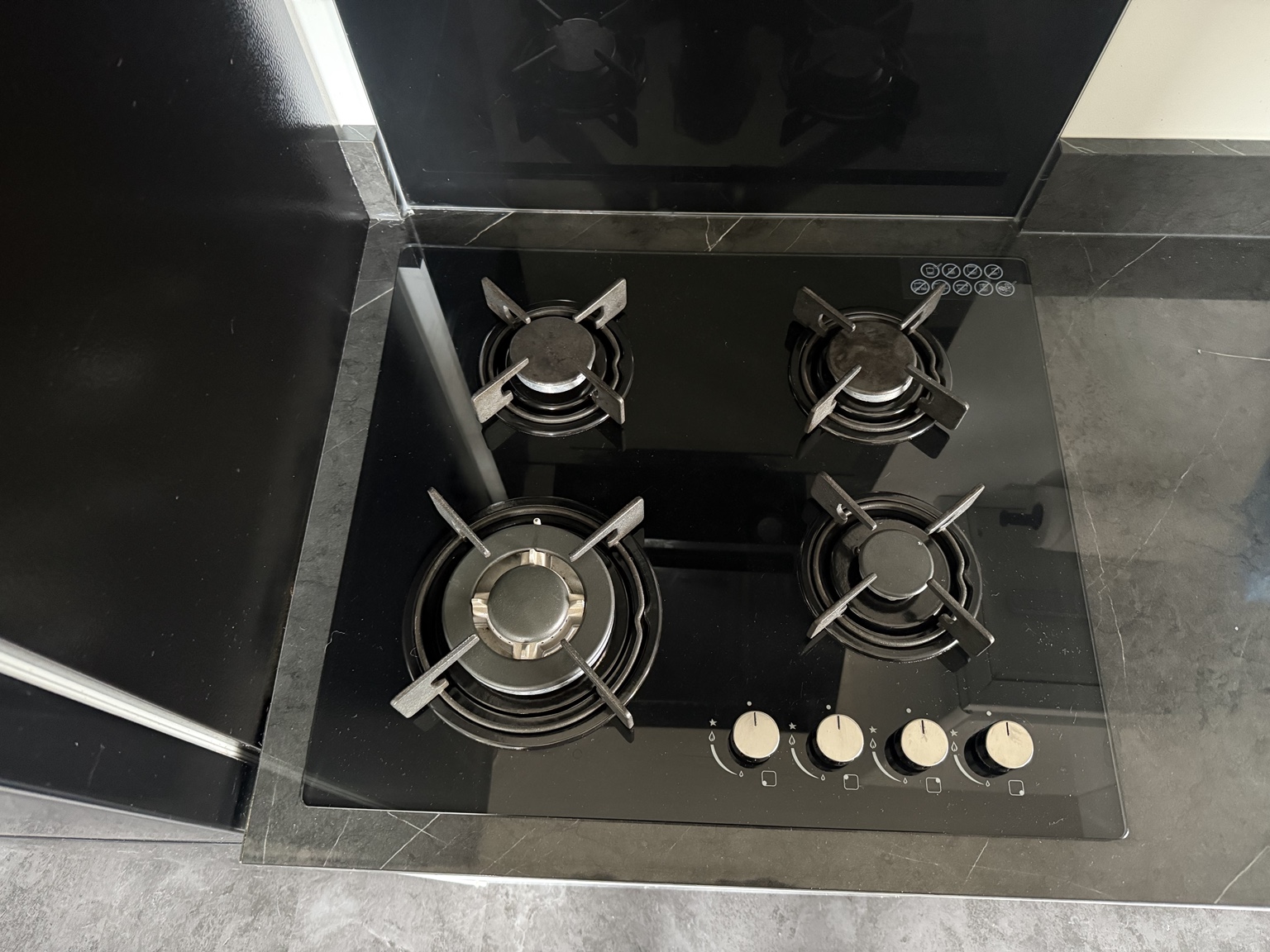 Black glass four-burner gas hob installed and tested in a modern kitchen in Manchester.